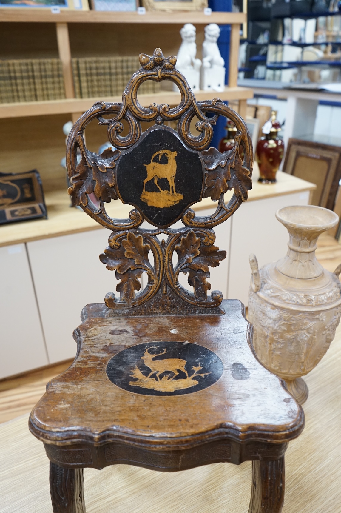 A 19th century Black Forest carved child’s musical chair with integral music box, the seat and back each inlaid with an animal cartouche, 68cm high